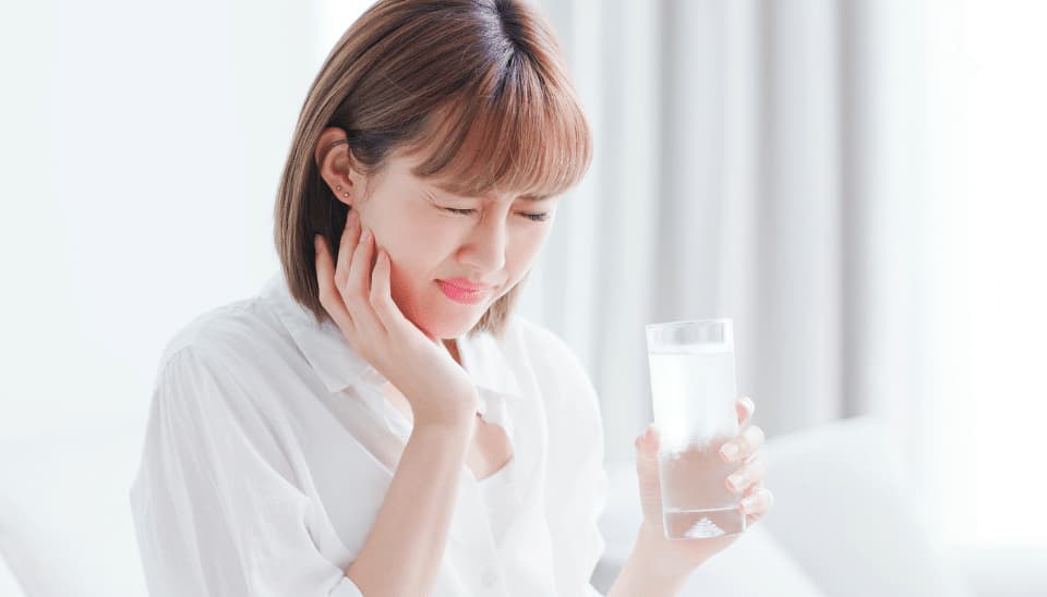 A female experiencing teeth sensitivity after whitening process