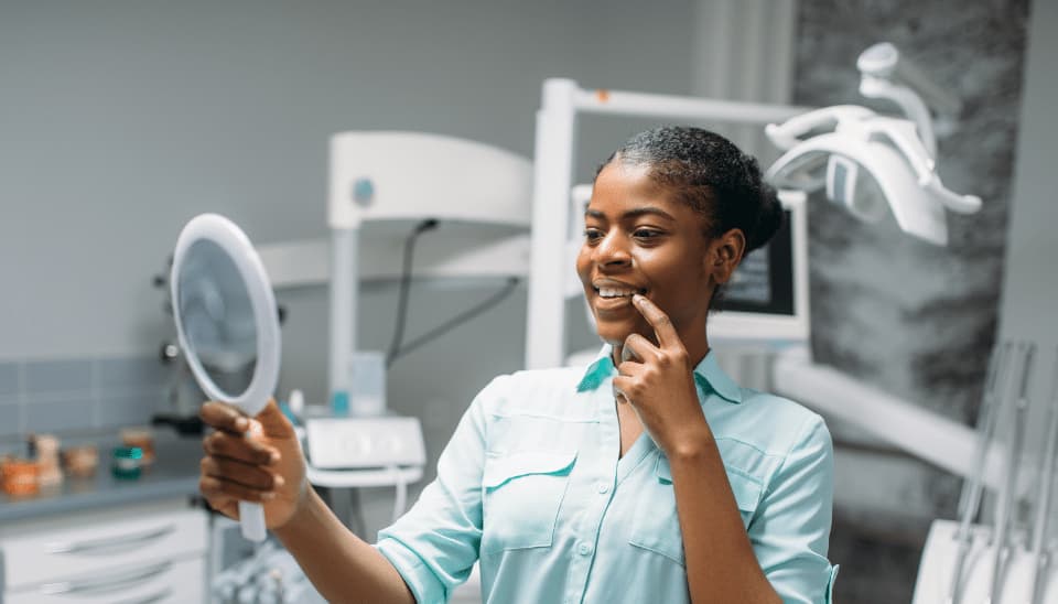 A female admiring her new dental crowns in a mirror