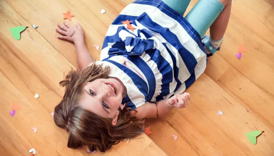 Child laying on floor with mouth open smiling