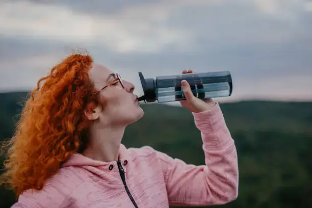 Woman drinking water, illustrating the importance of staying hydrated to support good oral health.