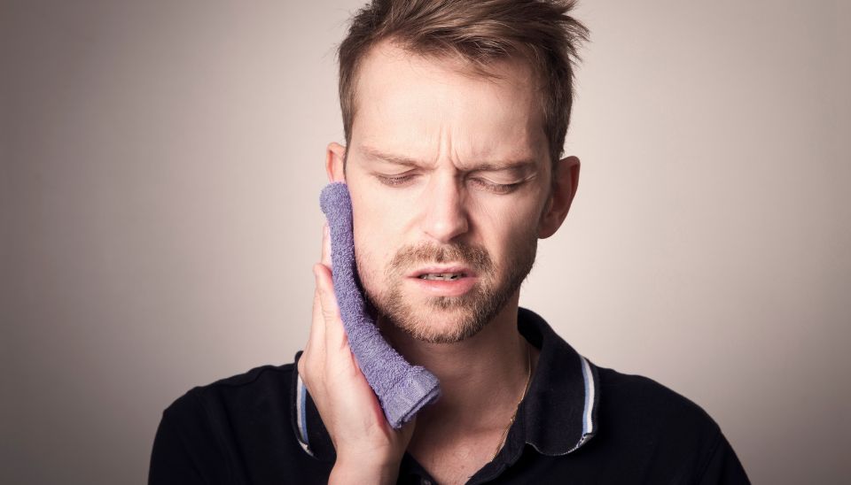 Man applying a cold compress to sever tooth pain